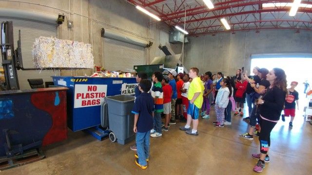 Children looking at recycling bin in a recycling facility