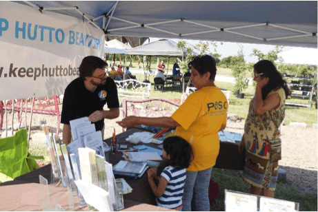 Man behind booth interacting with two women and a child